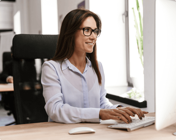 A woman smiles as she works on a computer