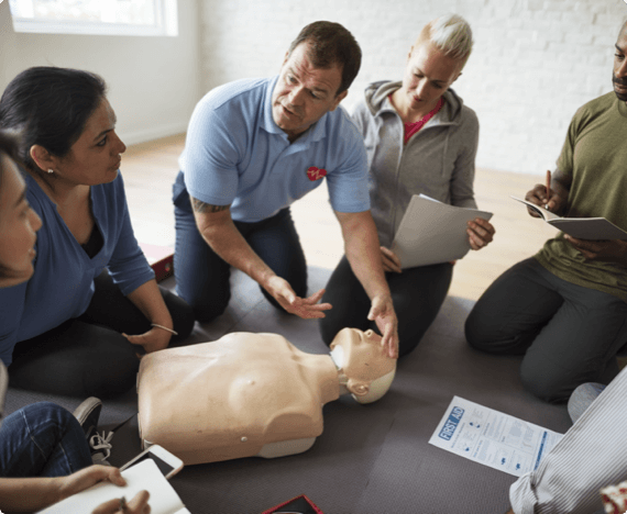 Health & Safety Sessions_ General img 1 A health and safety instructor teaches CPR on a practice dummy