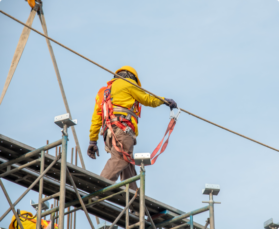 Health & Safety Sessions_ industrial img 1 A construction worker walks on scaffolding wearing a safety harness