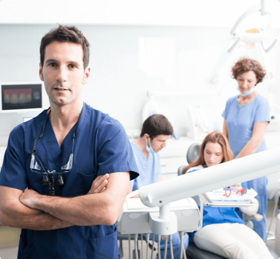 WHIMS health img 1 A dentist looks on as a patient sits in his chair surrounding by dental hygienists