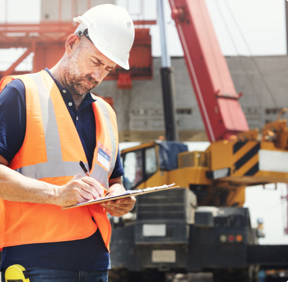 A workplace inspector takes notes on a clipboard