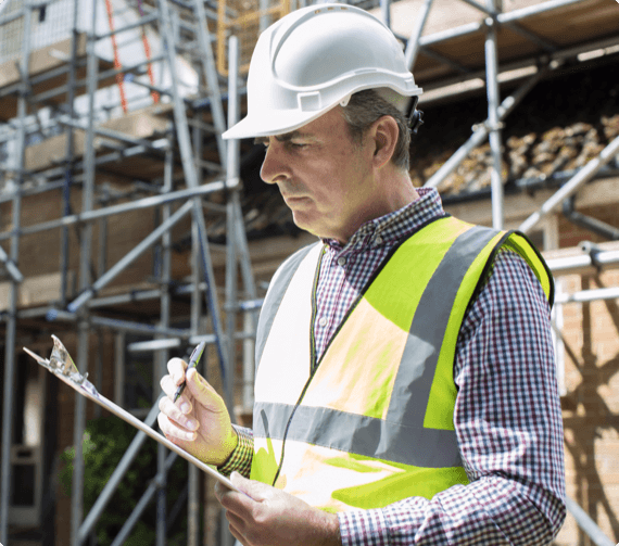 why us img 1 A safety inspector takes notes with scaffolding in th ebackground