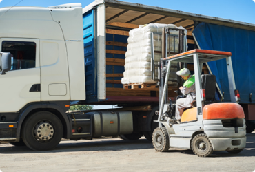 A forklift operator places a full pallet onto a semi truck