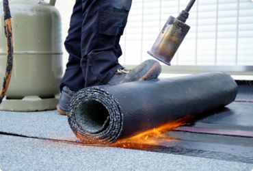 A worker uses propane on a construction site to lay down flooring