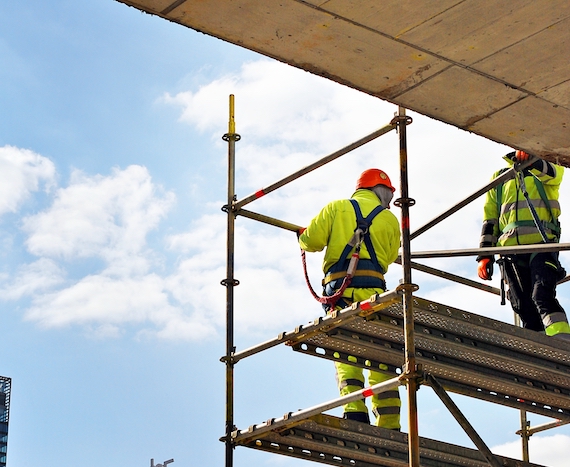 Scaffold Training Two construction workers wearing harnesses work safely on scaffolding
