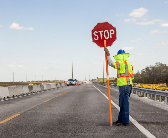 construction worker holds stop sign on roadway