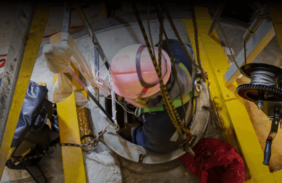 A worker is lowered into a tight and enclosed space