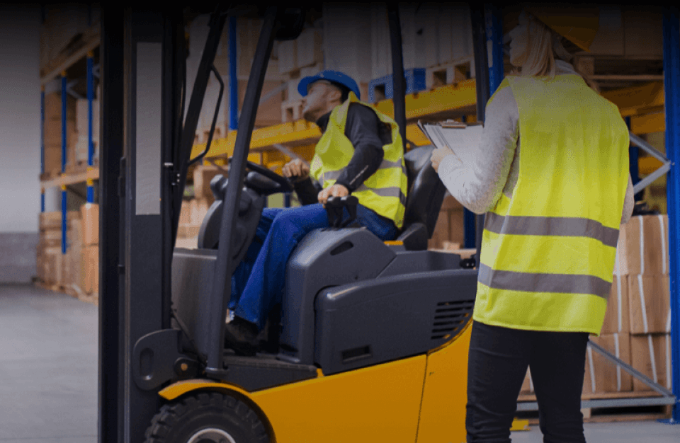 A manager speaks to a man operating a forklift