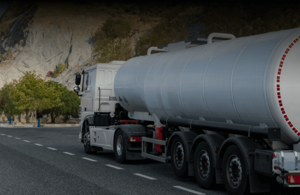 A large truck carrying dangerous materials drives down a road